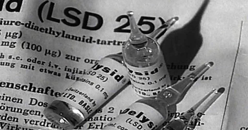 Black-and-white image of three glass ampoules labeled “Delysid (LSD 25)” resting on a printed instruction sheet with German text describing lysergic acid diethylamide dosages and usage.